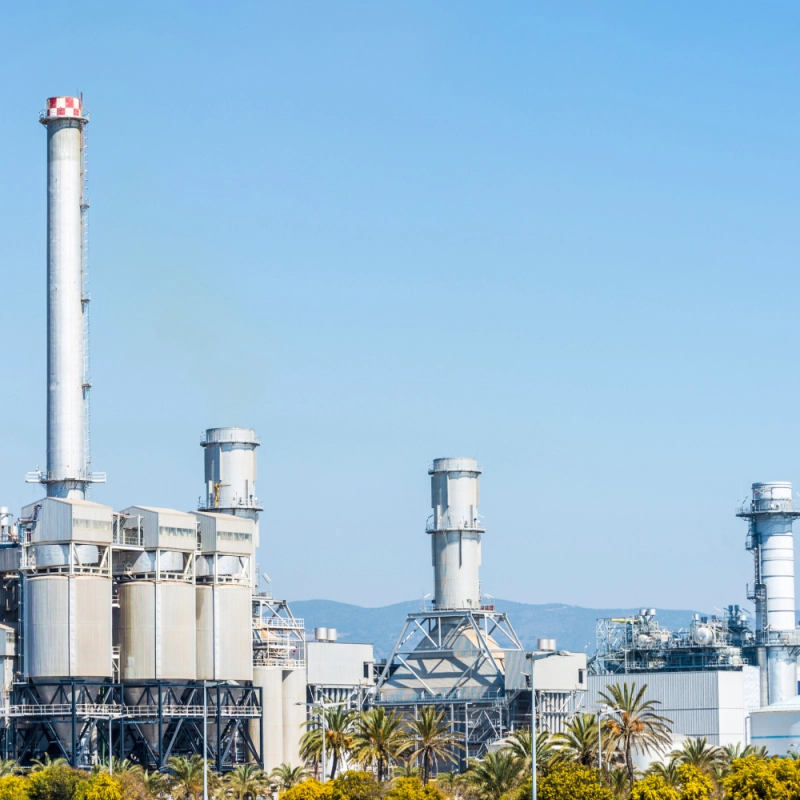 Fotografía Planta de tratamiento de residuos con maquinaria industrial y montones de materiales reciclables.